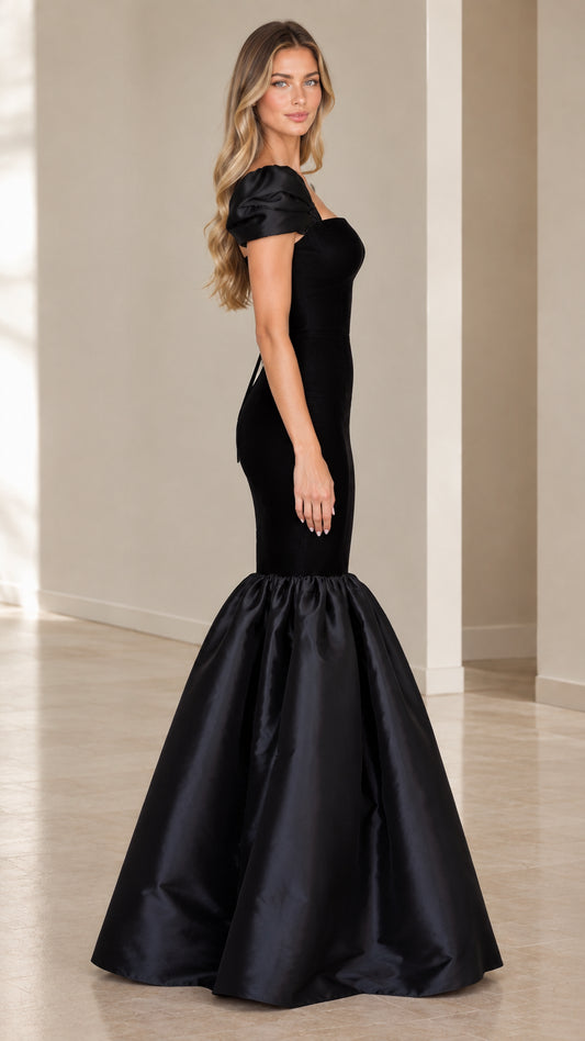 Side profile of woman wearing black fitted mermaid gown with flared hem