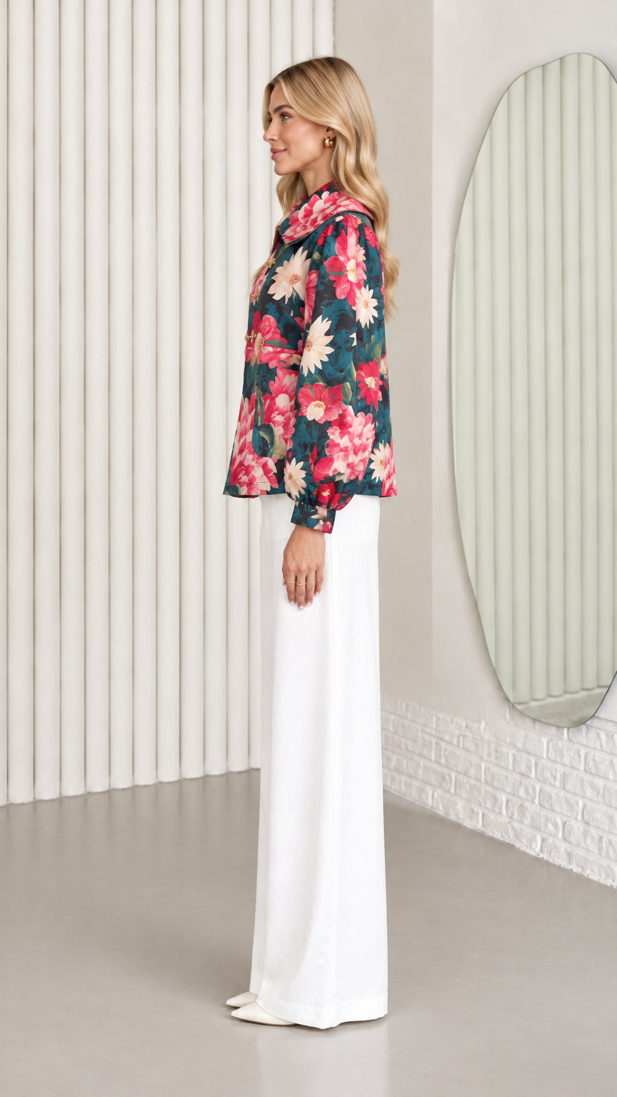 Side profile view of dark teal floral collared jacket paired with white trousers