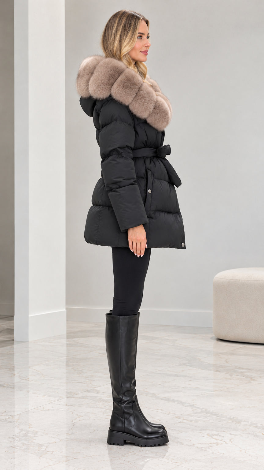 Side angle view of model in black hooded quilted jacket with tie waist