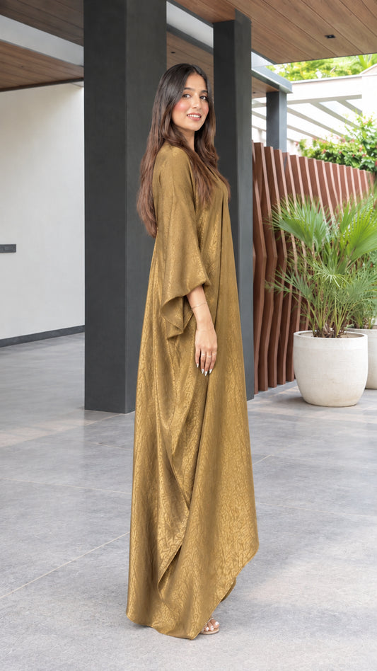 Side profile view of model wearing a flowy gold textured kaftan maxi gown