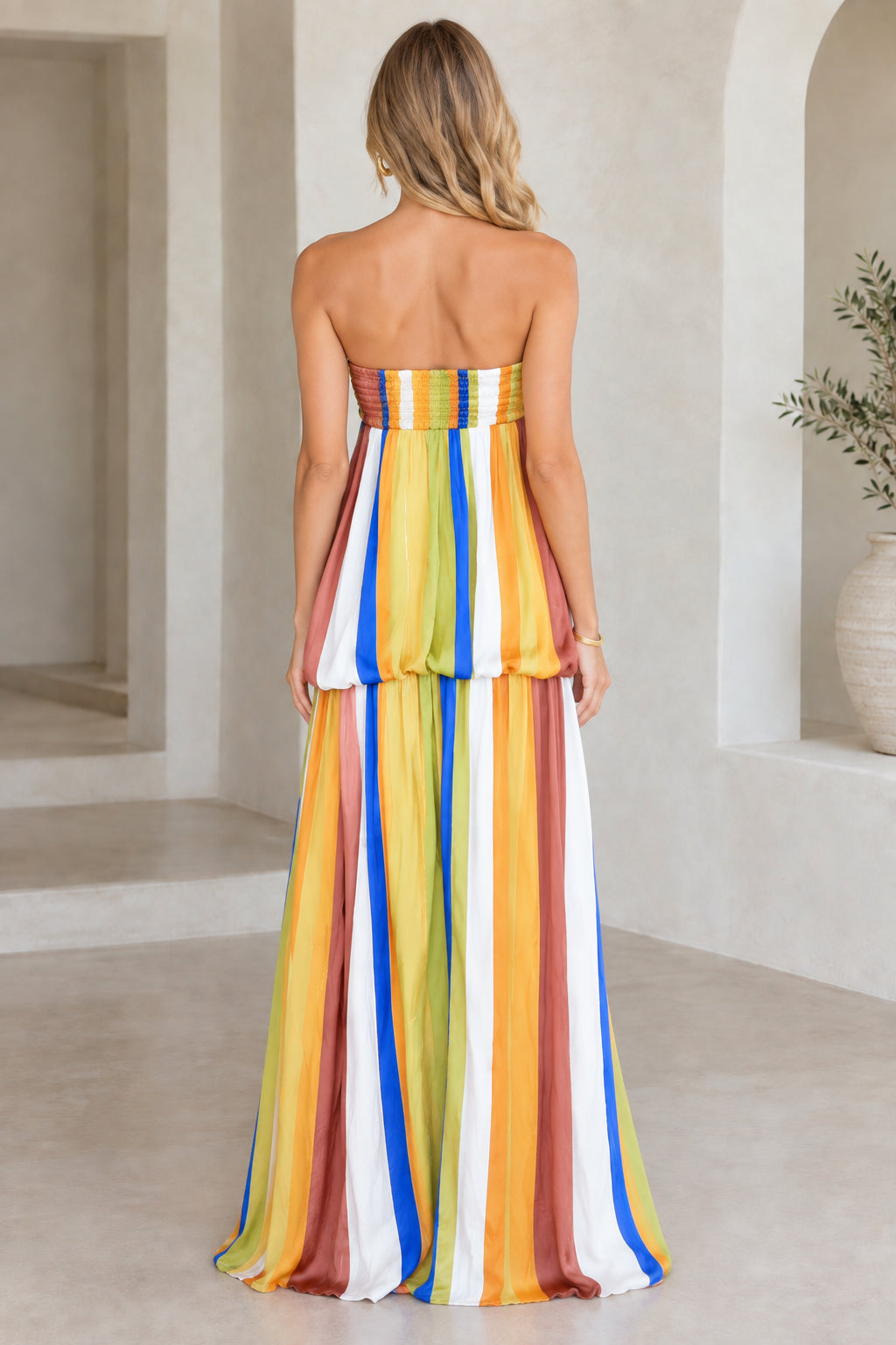 Back view of model in rust multicolor strapless striped maxi dress