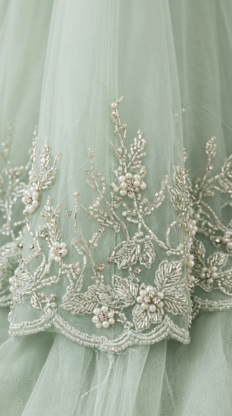 Close-up detail of floral beadwork, embroidery, and pearl accents on tulle fabric