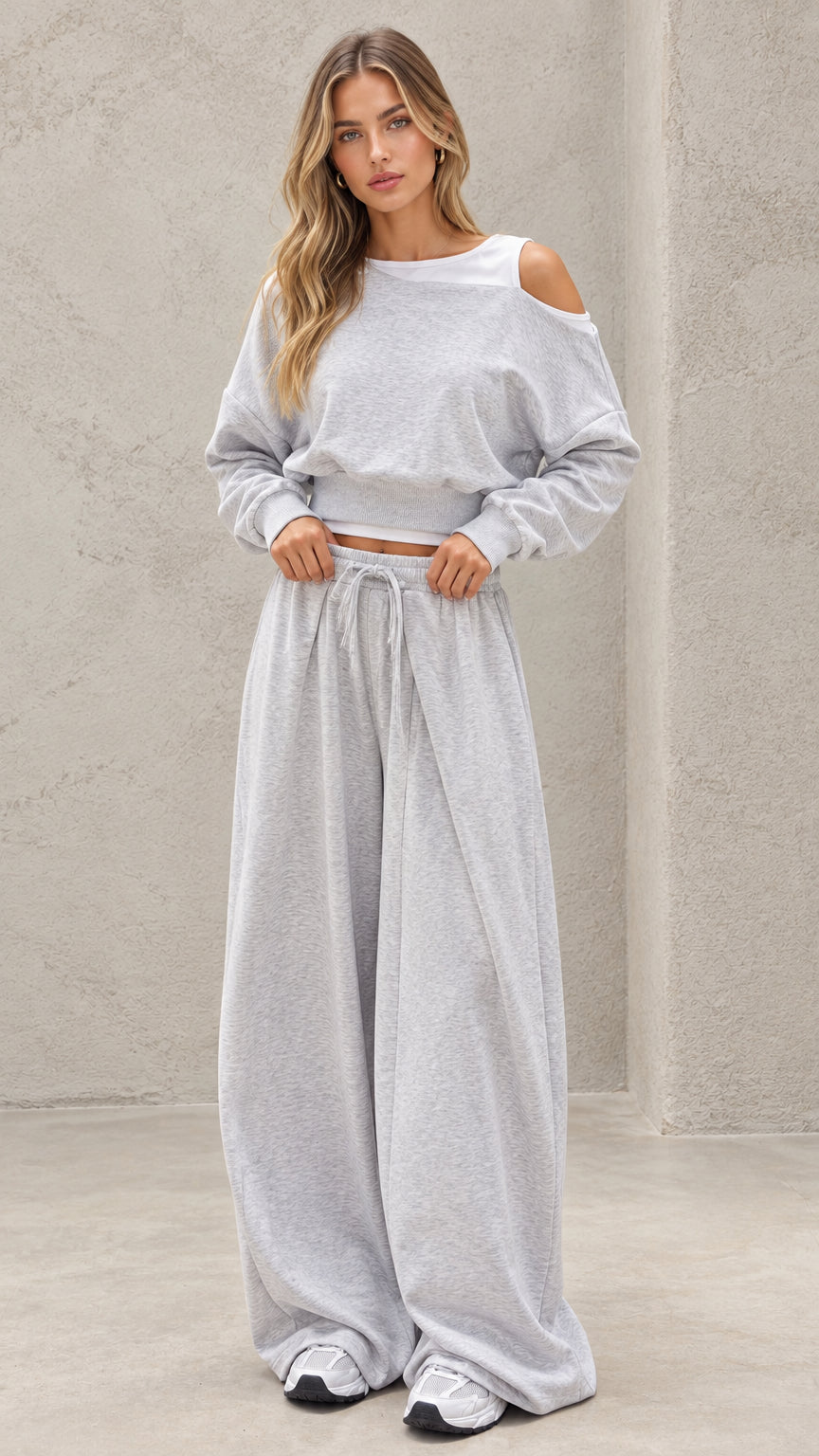 Front full-length view of model wearing heather grey cold shoulder cropped sweatshirt and wide leg pants set