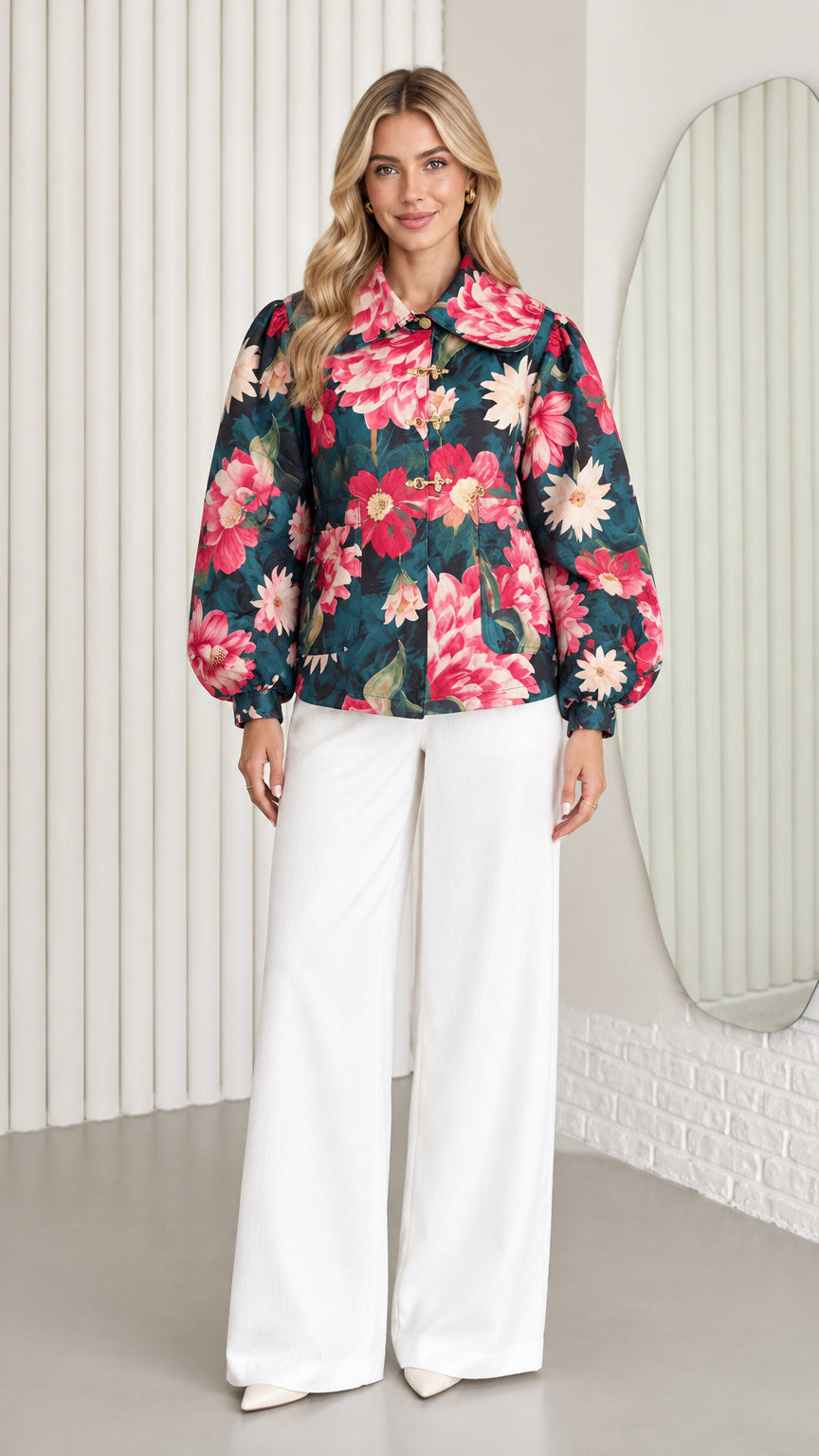 Front full-length view of model wearing dark teal floral jacket with balloon sleeves and white wide-leg trousers