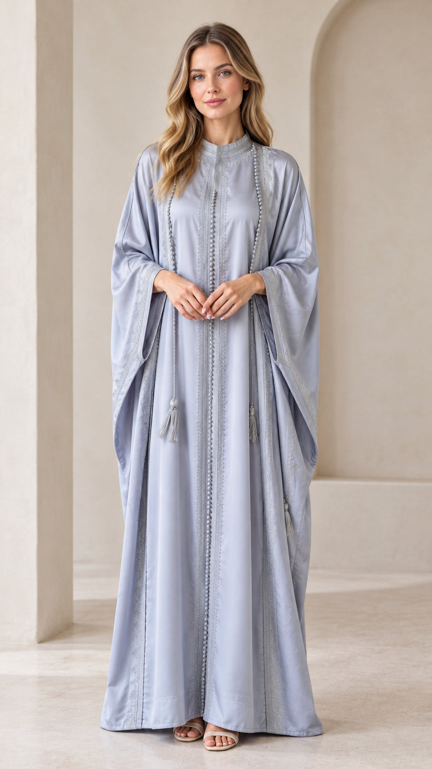 Front full-length view of woman wearing Dusty Blue embroidered batwing kaftan maxi dress with tassels
