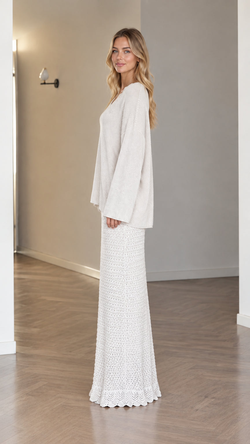 Side profile of model in cream two-piece long sleeve knit sweater and skirt set