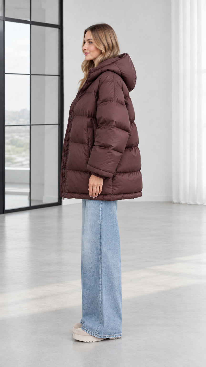 Side profile view of model in chocolate brown quilted hooded puffer jacket