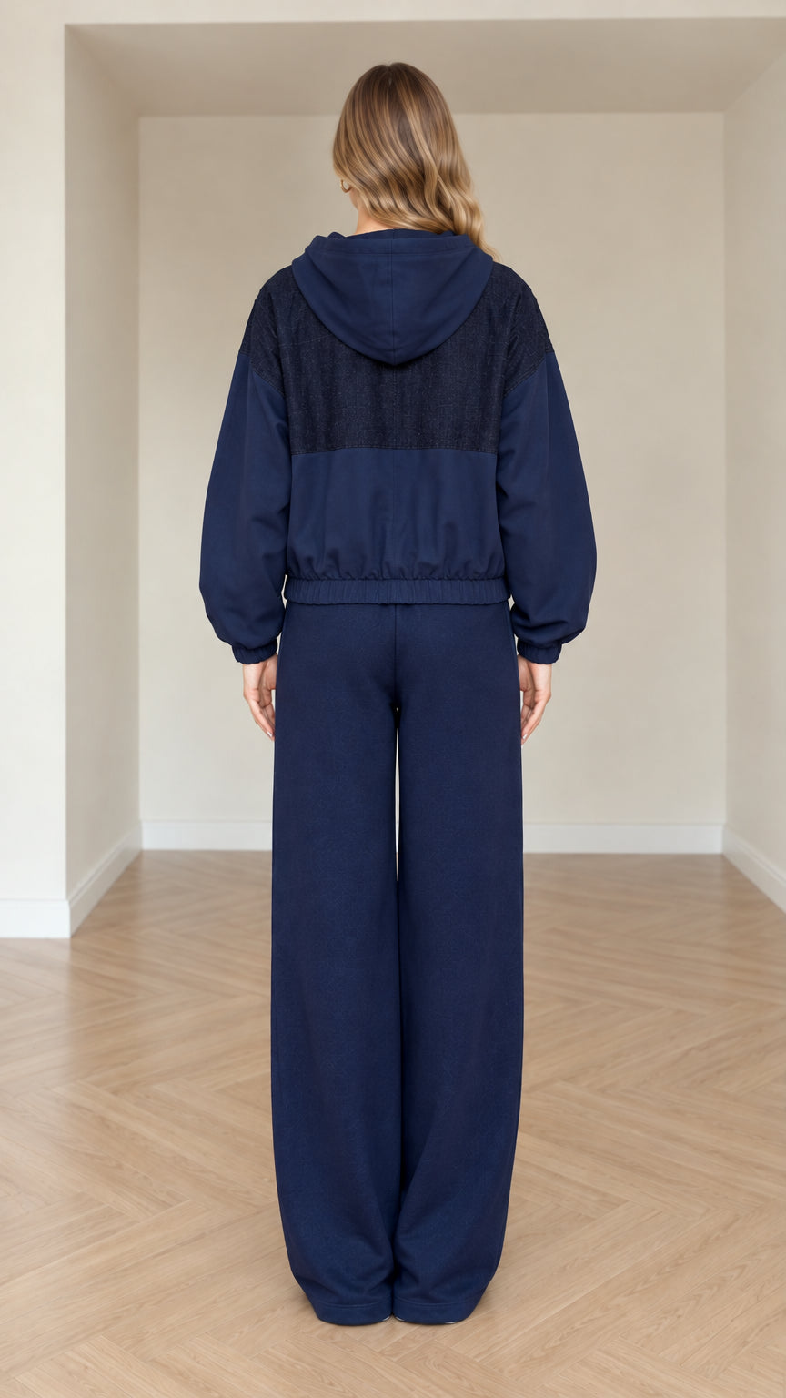 Back view of model in navy blue hooded tracksuit jacket and wide-leg pants