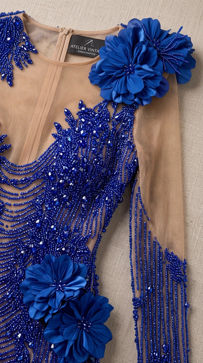 Close-up detail of mesh neckline, blue beadwork, and handcrafted 3D floral applique