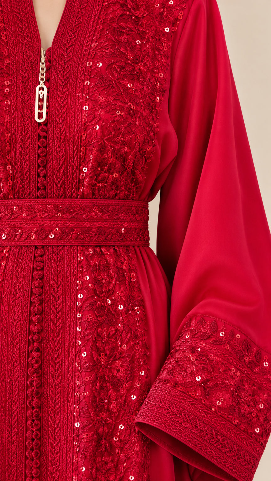 Close-up detail of red embroidery, sequin embellishment, belt, and neckline charm