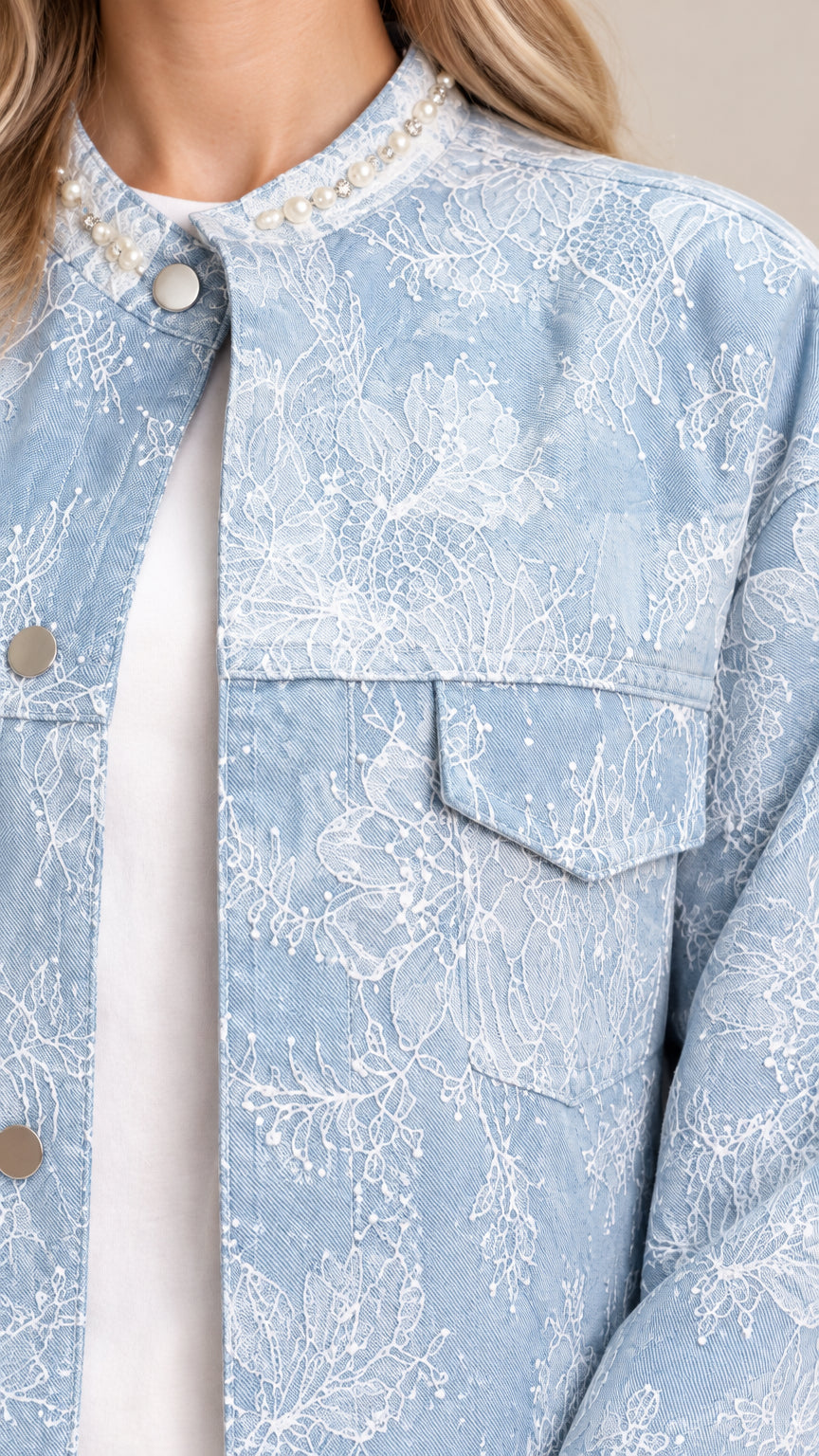Close-up detail of pearl-embellished neckline and floral embroidery on light blue jacket