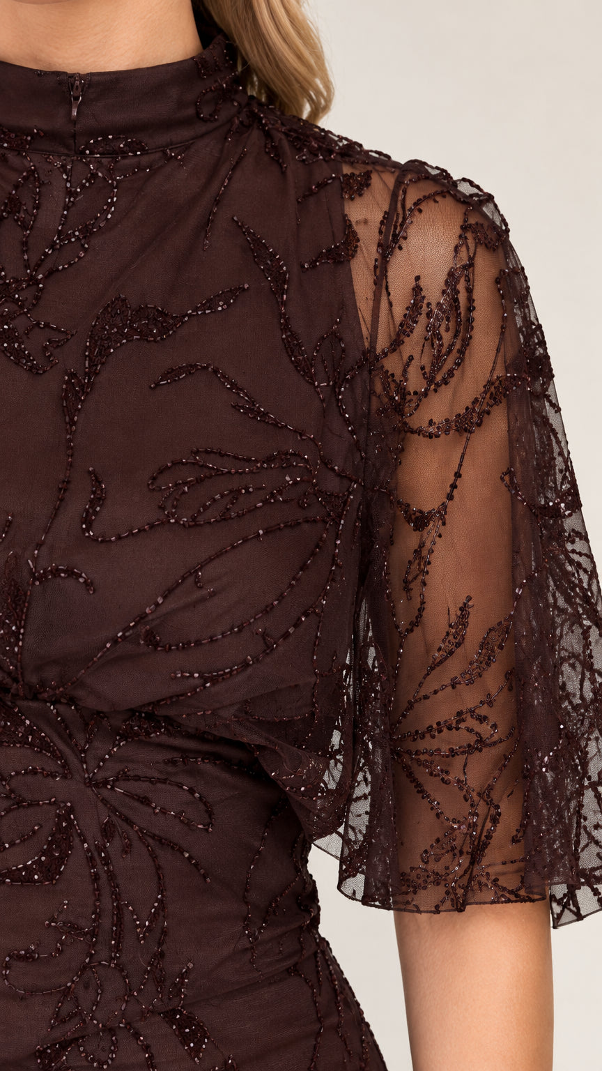 Close-up detail of sheer flutter sleeve and intricate botanical beadwork on brown dress