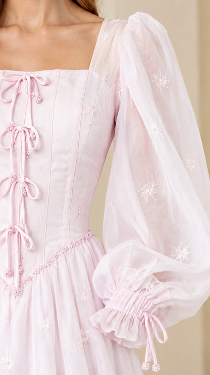 Close-up detail of lace-up bodice and embroidered sheer puff sleeve with ruffled cuff