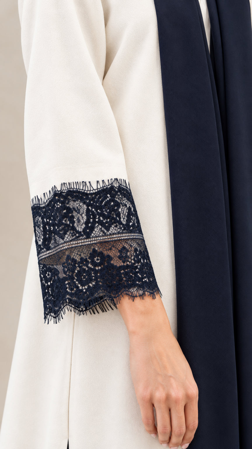 Close-up detail of dark floral eyelash lace cuff trim and flowing fabric