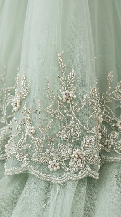 Close-up detail of floral beadwork, embroidery, and pearl accents on tulle fabric